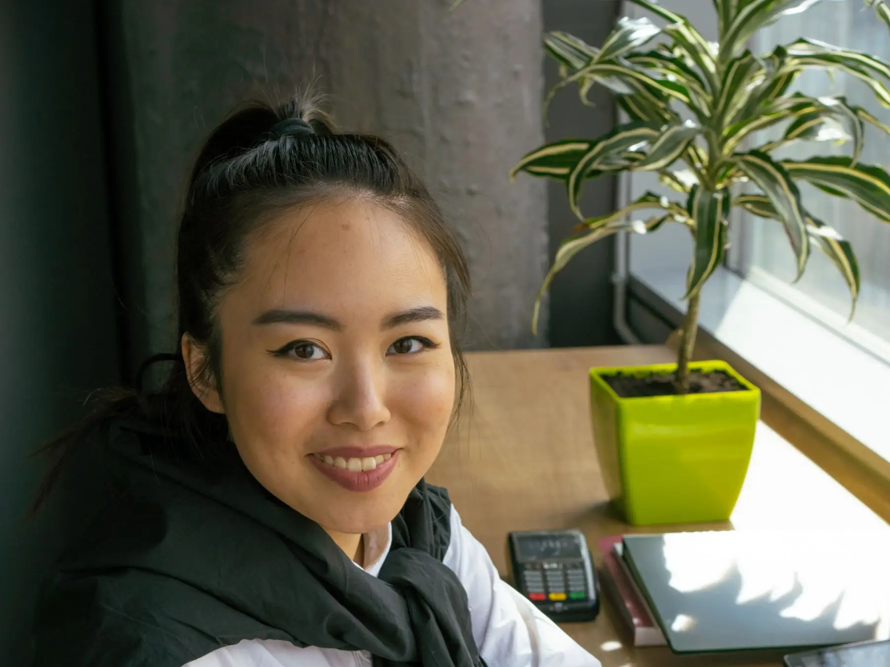 A smiling student working through figures with a calculator and laptop