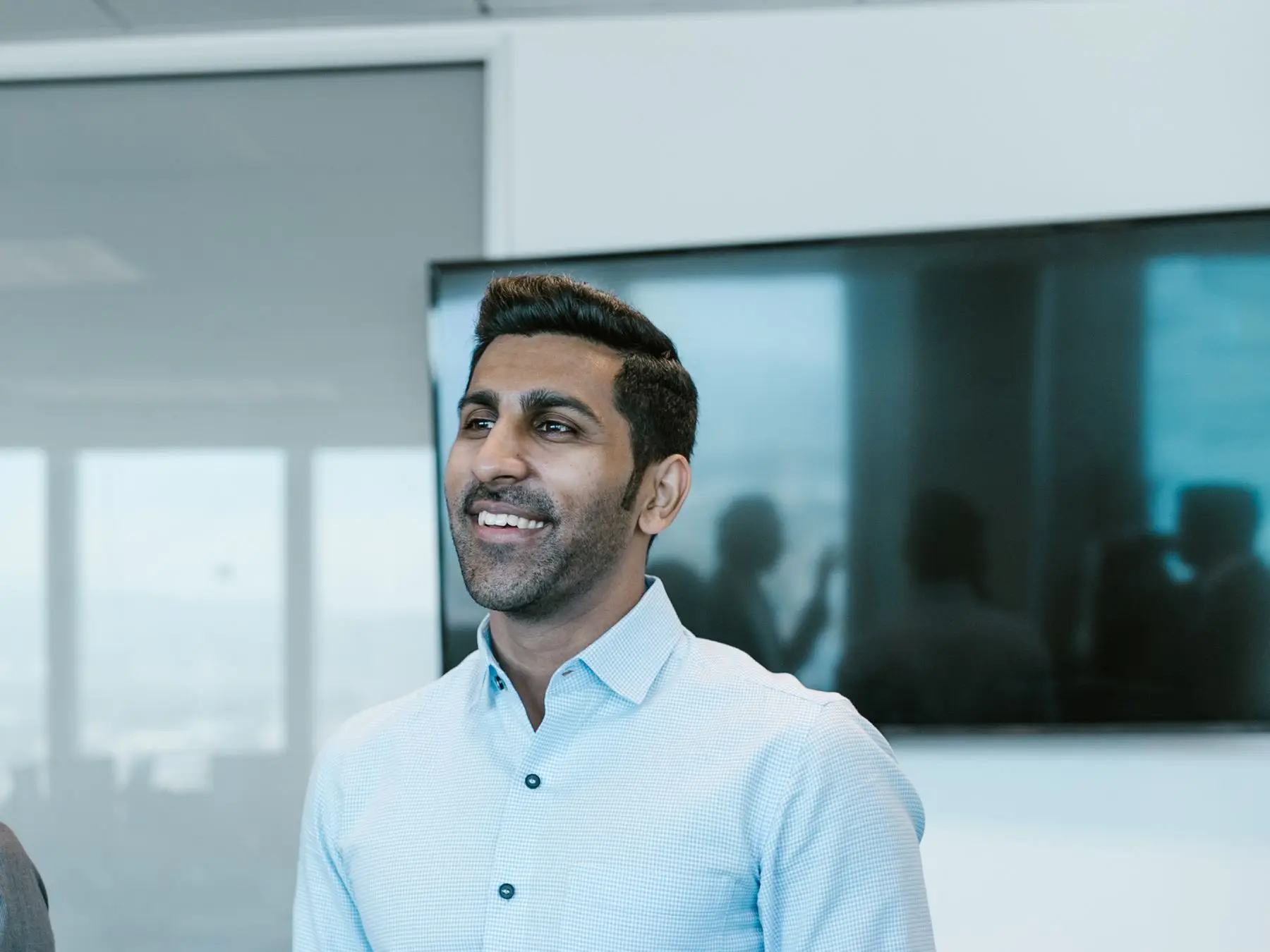 A smiling young professional presenting to colleagues in a bright office