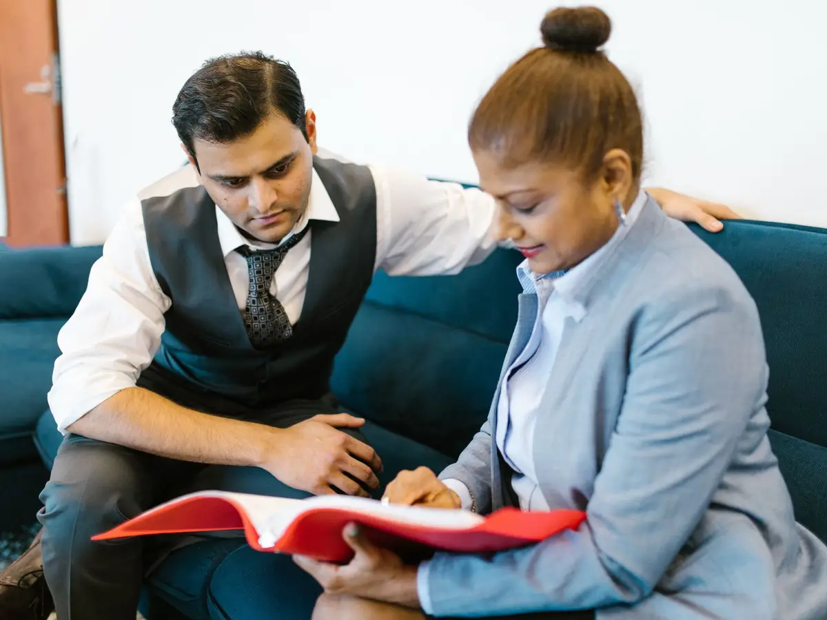 A counsellor and a client going through a red folder of documents together