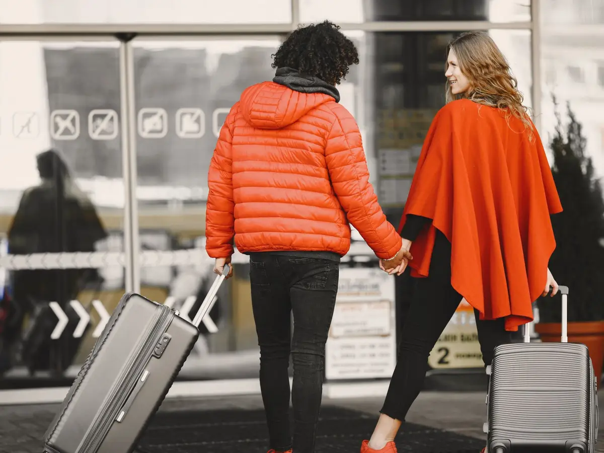 A couple with suitcases walking hand in hand through an airport