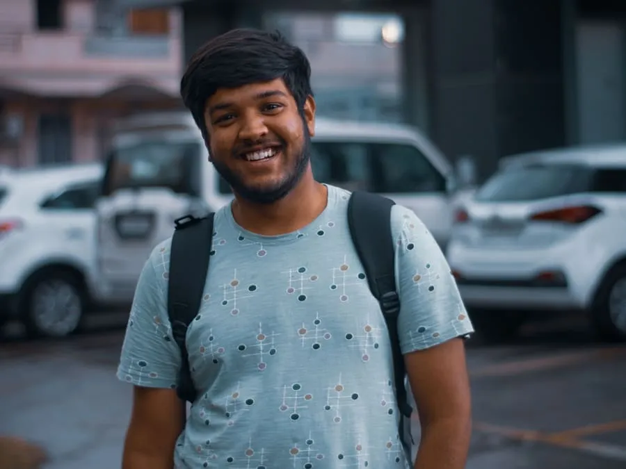 Dipak smiling with his backpack on, outside an office building