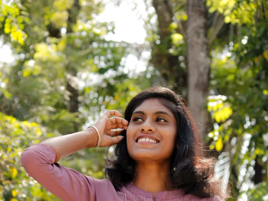 Kabita smiling under the trees in a pink kurta