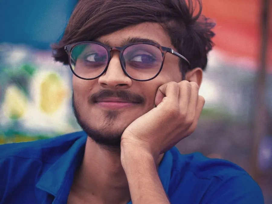 Aakash in glasses, smiling with his chin on his hand