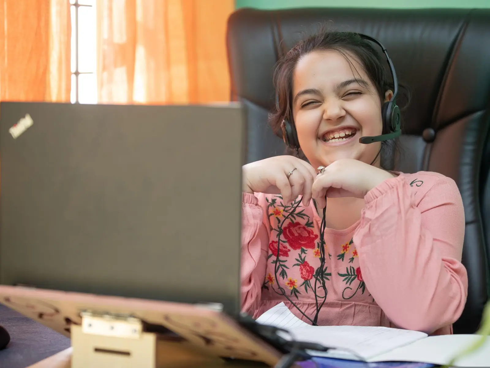 A student in a headset laughing during a practice session on a laptop