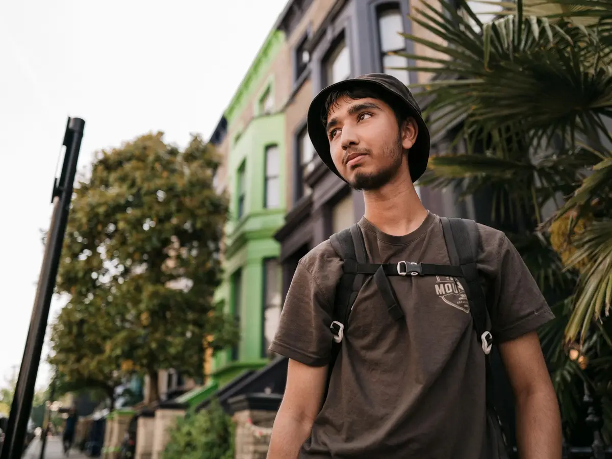 A young man with a backpack on a residential street in London
