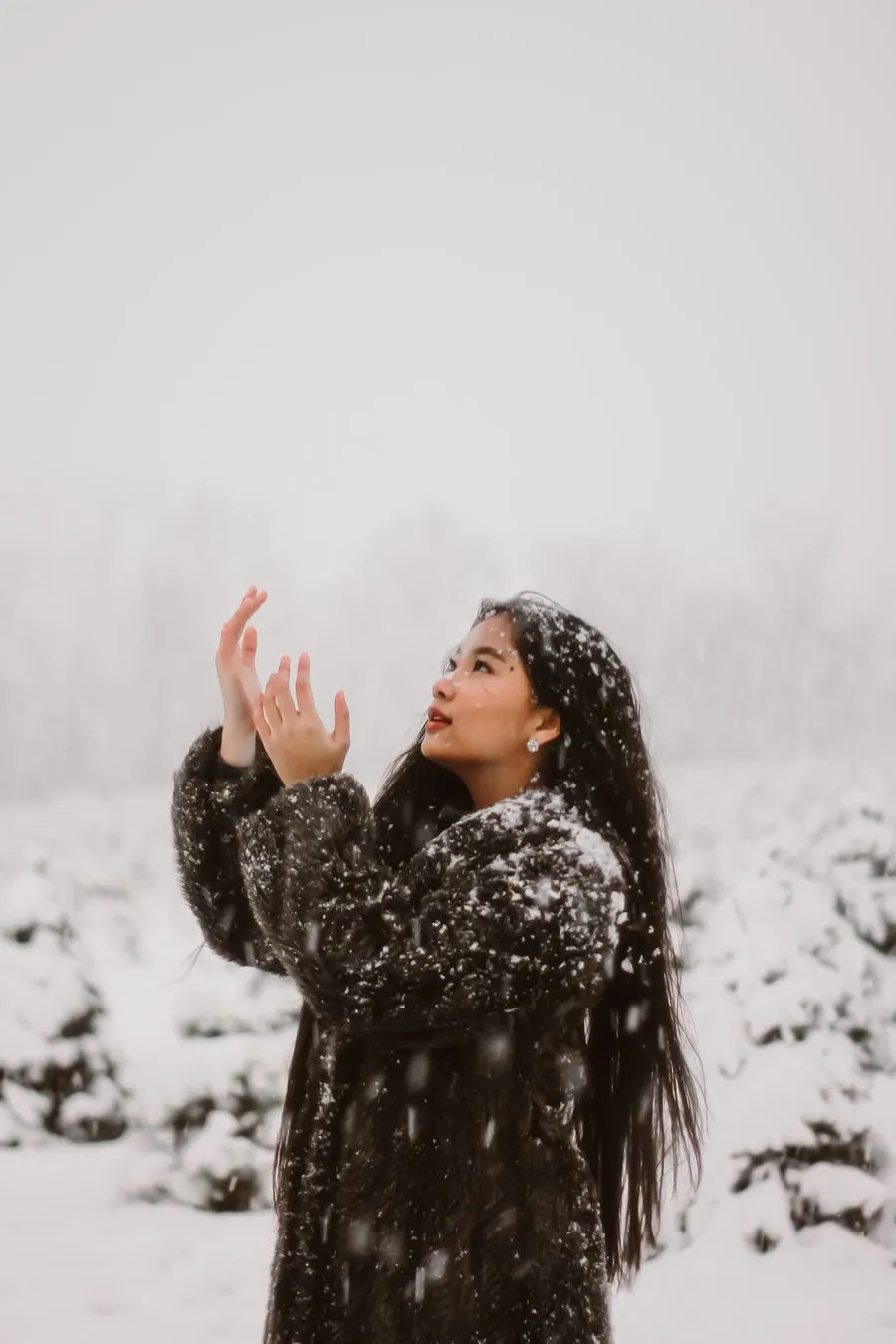 Pema reaching up to catch falling snow in Norway