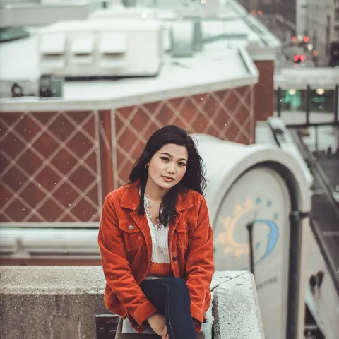 A student sitting on a snowy rooftop above a city in Sweden