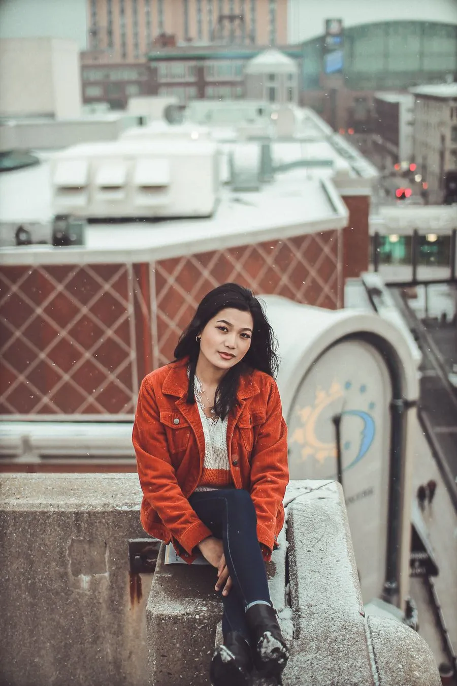 Sneha sitting on a rooftop above a Swedish city street