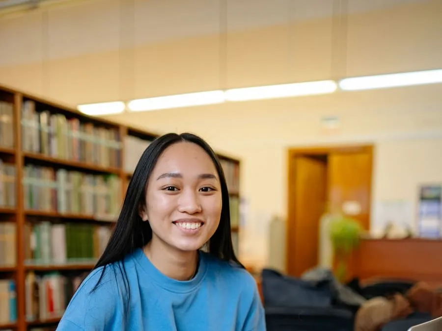 Prerana smiling at a desk in a library
